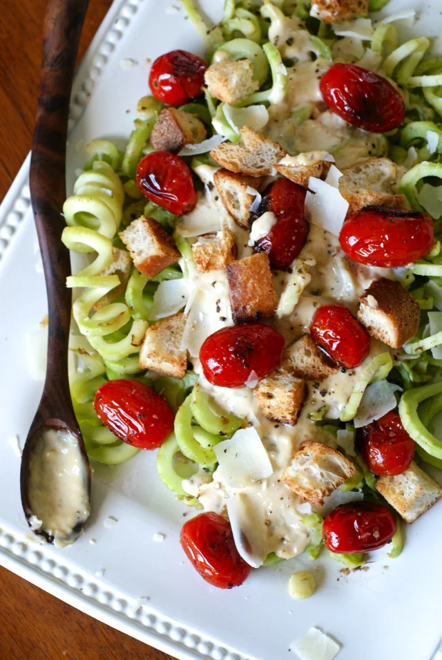 Caesar-Style Spiralized Broccoli with Blistered Tomatoes transforms broccoli stalks into a delicious side dish topped with garlicky caesar dressing, pan seared tomatoes, croutons, and parmesan cheese.