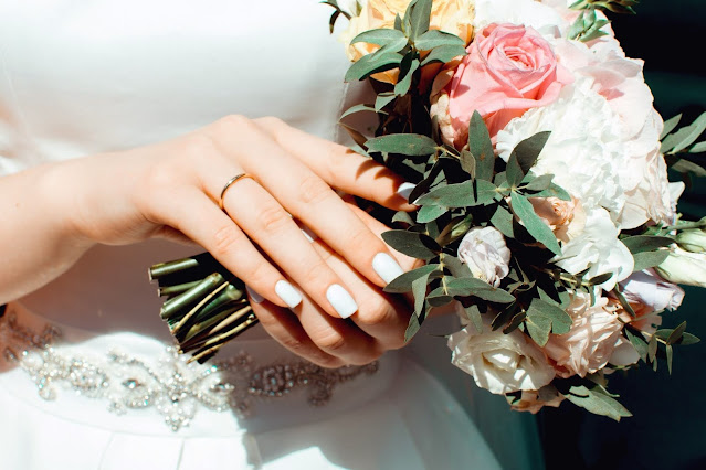 Close up of a bride's hand with her wedding ring and bouquet in focus.