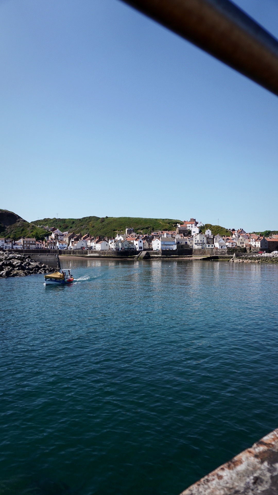 view looking back to a seaside village, a boat is leaving the harbour