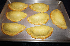 EMPANADAS DE VACUNO JAMAIQUINAS PORCIONES: 27 EMPANADAS INGREDIENTES PARA EL RELLENO 2 cucharadas de aceite de vegetal 800 g. de cebolla picada 3 dientes de ajos picados 1 kg. 220 g. / 2.70 lb. carne de vacuno molida 2 cucharaditas de curry 1 cucharadita de pimienta inglesa 2 cucharaditas de tomillo seco o 4 de tomillo fresco ¼ cucharadita de pimienta negra en polvo 2 cucharaditas de sal 2 cucharaditas de paprika o ají de color 1 cubito de caldo de vacuno sin glutamato mono sódico 1½ tazas de agua caliente 1¾ tazas de pan rallado Panko 1 taza de cebollines verdes, cortados en rodajitas PROCEDIMIENTO Calentar el aceite en una sartén a fuego moderado y sofreír la cebolla. Agregar la carne, revolver y cocinar hasta que quede cocinada, sin dorar. Agregar las especias y cocinar por un par de minutos. Disolver el cubito de caldo de pollo con el agua caliente, agregar a la carne junto con el pan rallado y revolver bien. Añadir y revolver los cebollines. Dejar a enfriar y por mientras hacer la masa para las empanadas. MASA PARA LAS EMPANADAS INGREDIENTES 1 kg. 600 g. / 3.97 libras de harina de trigo blanca, para todo uso. 3 cucharaditas de sal ½ cucharadita de curry ½ cucharadita de cúrcuma en polvo 400 g. de manteca de vegetal 2¾ tazas de agua bien fría PROCEDIMIENTO Mezclar bien la harina con la sal, curry y cúrcuma. Cortar la manteca en la harina con una batidora o sus dedos, que quede la harina con grumos pequeños. Agregar y mezclar en la harina el agua bien fría, formando la masa. No amase demasiado la masa. Puede agregar un poquito más de agua si es que es necesario. Poner la masa en el refrigerador por 1 hora. Cortar la masa y hacer bolitas de 100 g. / 3.5 oz. cada una. Con un rodillo estirar la masa de las bolitas, formando un círculo de 17 cm. / 6¾”. Rellenar los discos con la carne. Mojar los bordes, cerrar la masa formando una media luna y apretar los bordes con un tenedor. Poner las empanadas en una bandeja de hornear y pintarlas con u1 huevo batido. Precalentar el horno a 232° C. / 450° F. Cocinar las empanadas por aproximadamente unos 25 minutos o hasta que los bordes de la empanada comienzan a dorar.