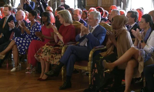 Queen Mathilde wore a red silk blouse and pattern midi skirt. Elman Peace of Somalia and King Baudouin Foundation