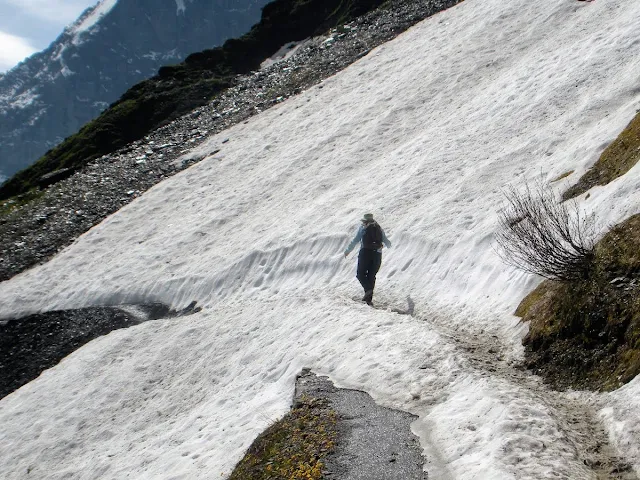 Jennifer from Sidewalk Safari blog walking on a narrow snow covered path between Männlichen and Kleine Scheidegg