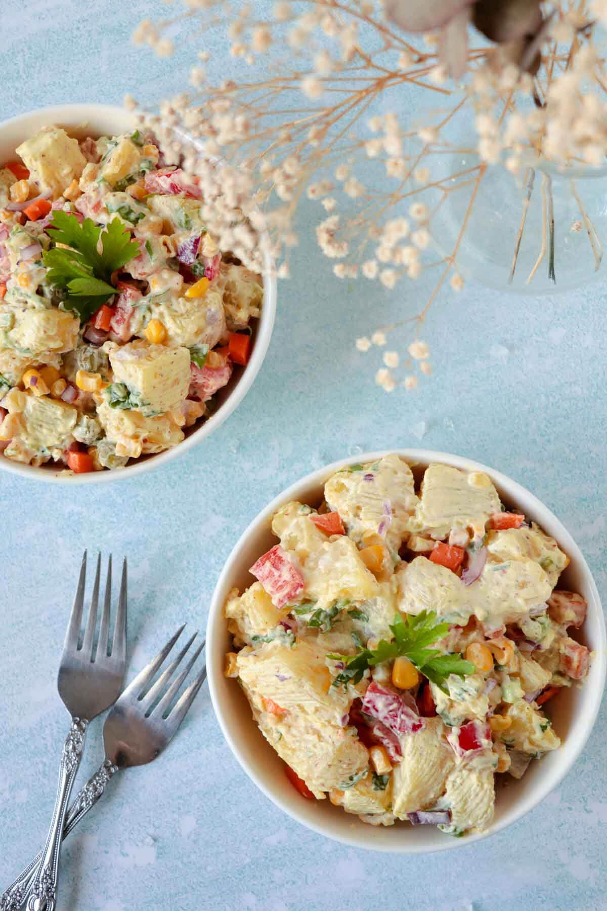 Two cream bowls full of Caribbean potato salad, garnished with parsley.