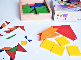 na zdjęciu widać układankę Tangram - pudełko, elementy w różnychy kształtach i kolorach oraz karty do odwzorowania