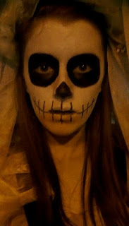 A close up of my bride of the dead makeup, featuring a skull-like look, with dark black eyes, white face and skeleton mouth, pulling a spooky, eyes-wide expression.