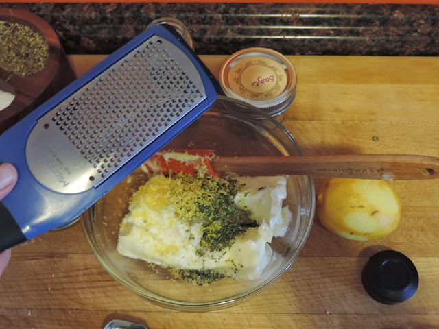 Lemon zest being added to the herbs and butter.