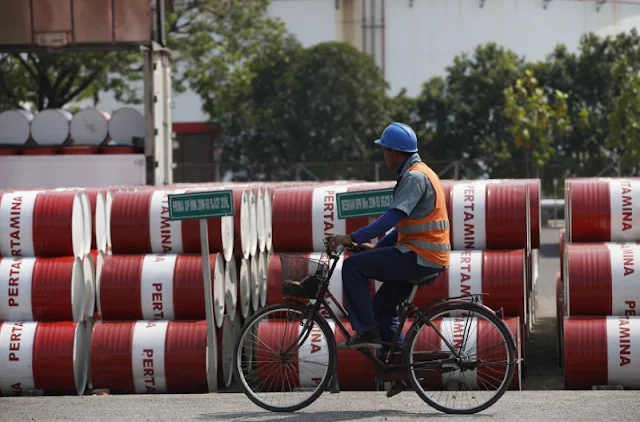 Image Attribute:  An employee rides his bike past barrels of petroleum products at a state-owned Pertamina fuel depot in Jakarta September 9, 2014. REUTERS/Darren Whiteside