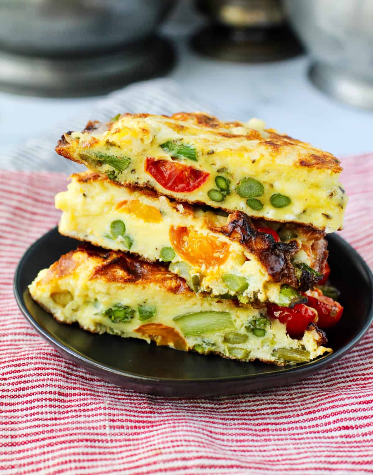 Asparagus Frittata with Cherry Tomatoes slices stacked on a plate.