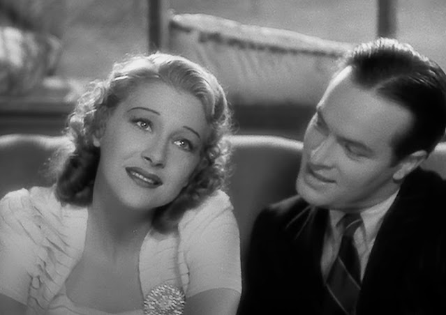 Screenshot from the 1938 movie Thanks for the Memory showing a close up of Shirley Ross and Bob Hope sitting on a couch, with Ross looking forward dreamily and Hope looking at her.