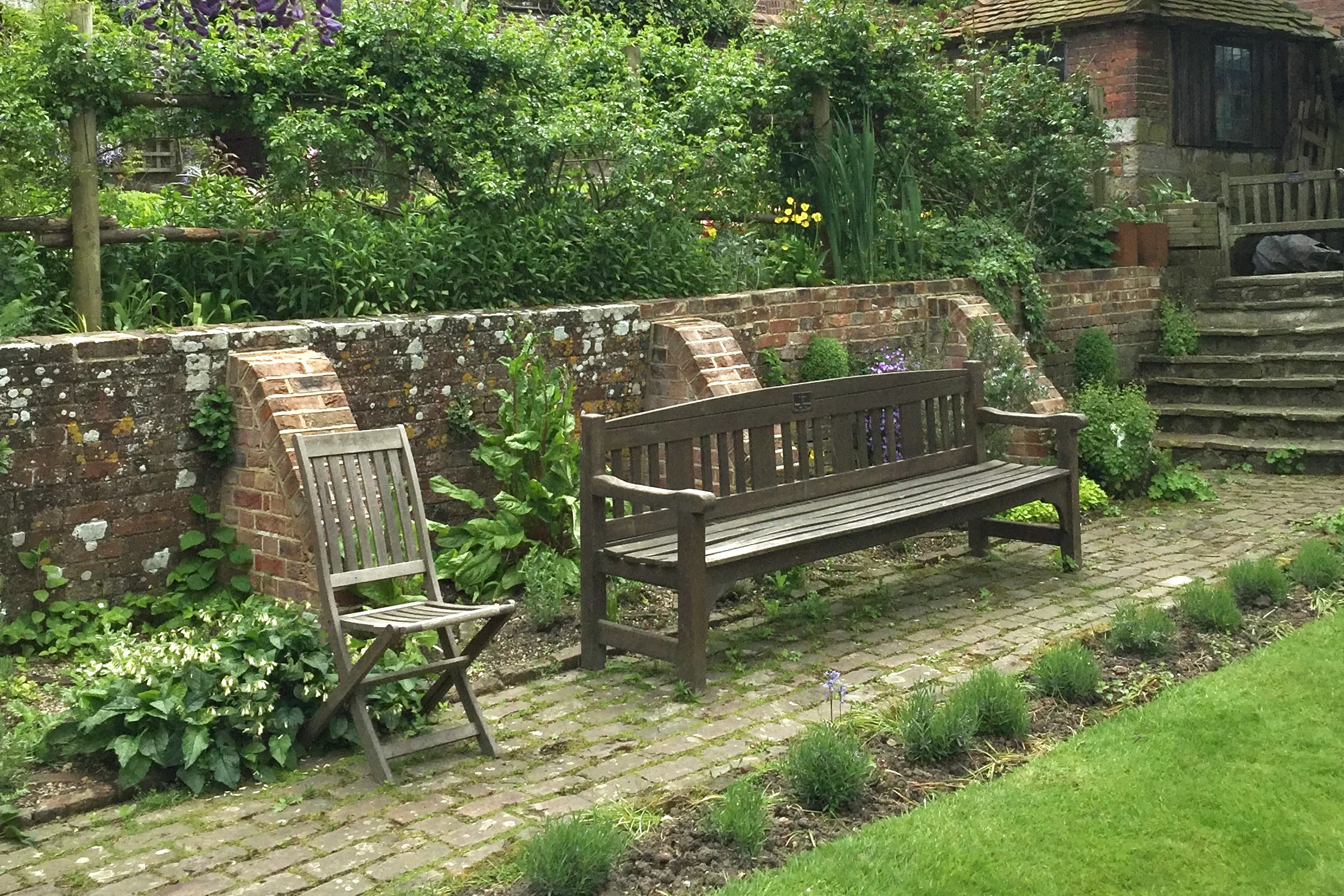 A walled garden with flowers and wooden seating