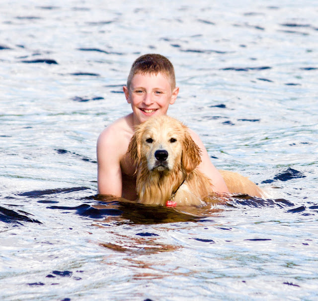 Boy and golden retriever in lake