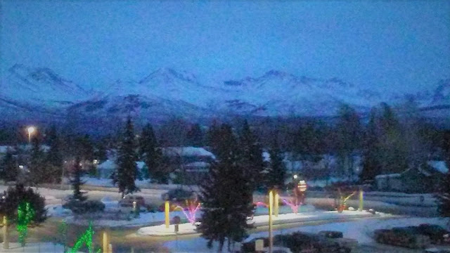 Alaskan town at sunset showing buildings, trees, and mountains