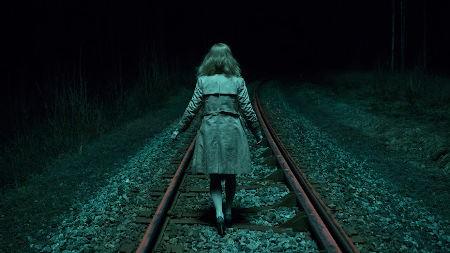 blue woman walking down train tracks