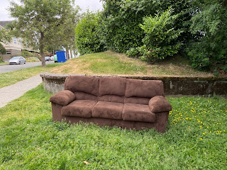 A brown couch on a green lawn in Seattle.
