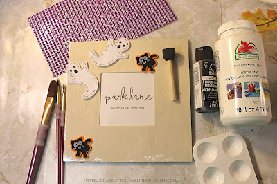 Craft materials such as ghost sticker, picture frame, paintbrushes, and craft gems