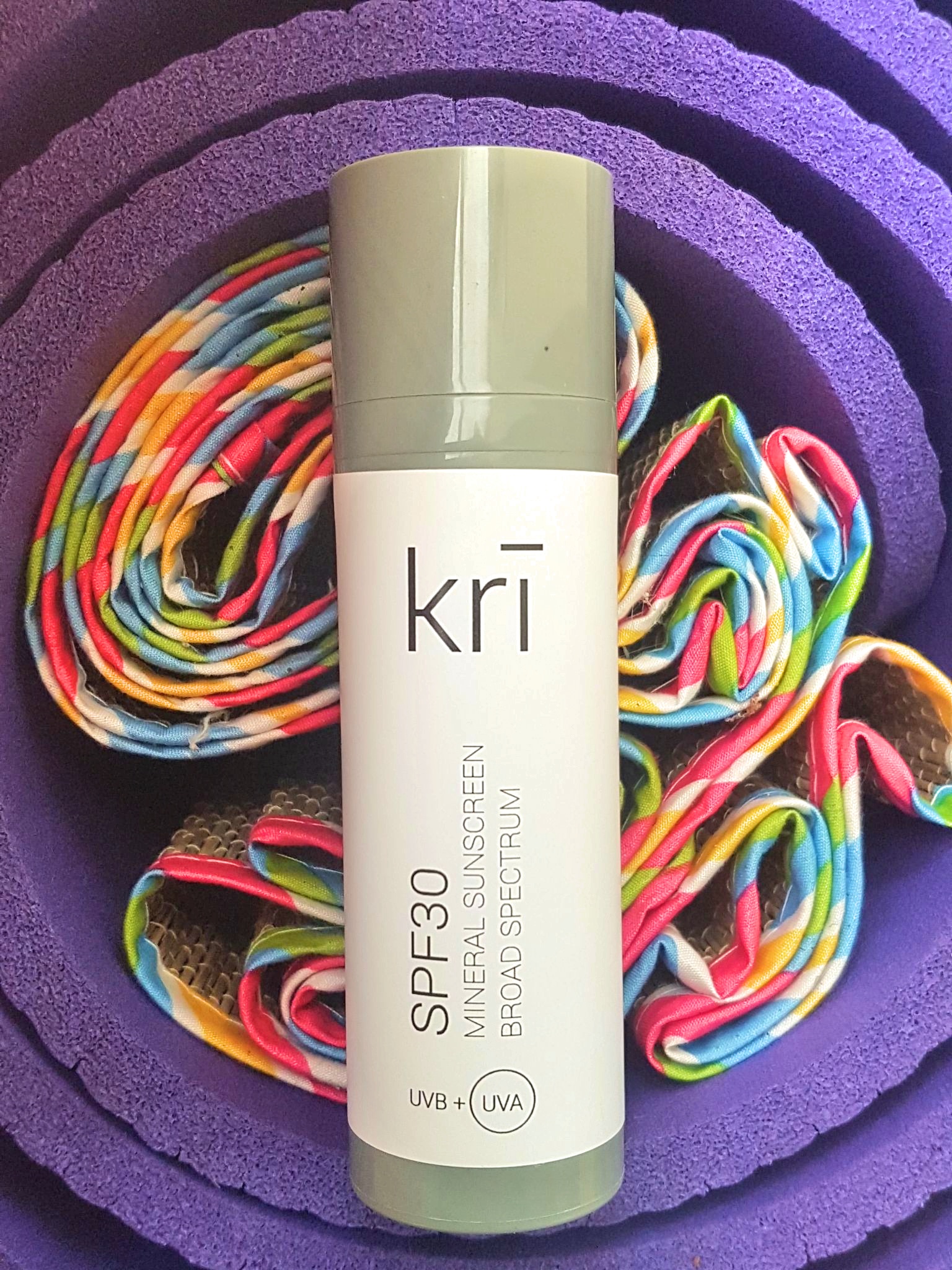 Kri Skincare SPF30 Mineral Sunscreen on top of colourful rolled up mats
