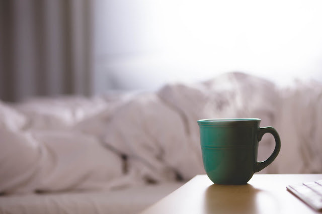 messy bed and a mug on the nightstand