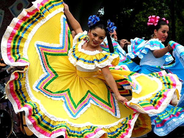 two pretty, dark-haired girls dance in colorful dresses with huge skirts