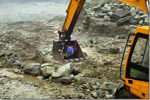 An excavator is used to move villagers away from a flooded area during heavy rainfall in Yingxiu, Wenchuan county, Sichuan province, China, July 10