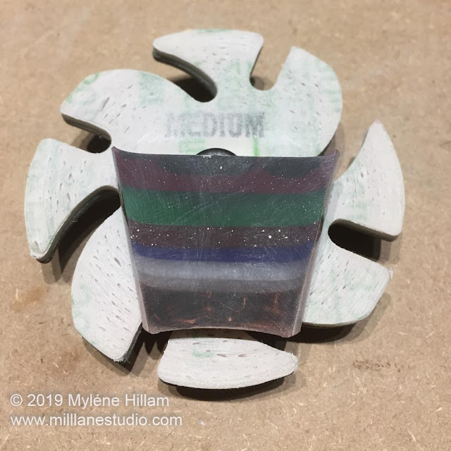The resin slice is sitting on a medium sanding disk