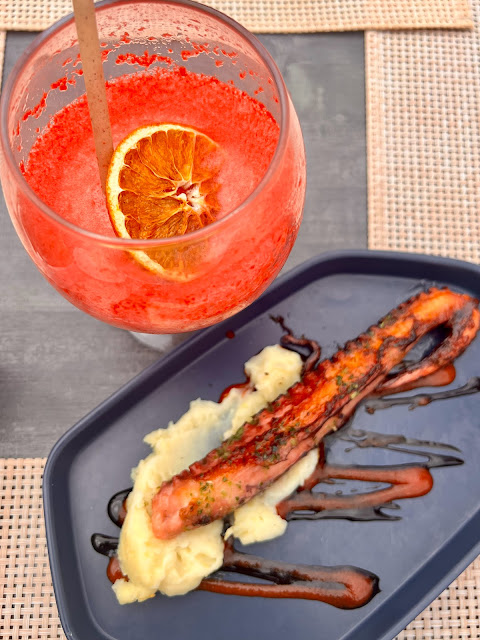 Octopus leg with paprika and mash and a glass with frozen strawberry daiquiri in.