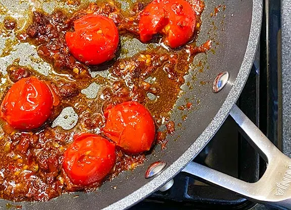 Rose harissa with tomatoes in a frying pan.