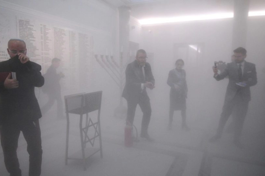 Momento em que Grzegorz Braun (ao centro) apagou com um extintor de incêndio as velas de uma menorá, o candelabro símbolo do judaísmo | Foto: EFE/EPA/MARCIN OBARA