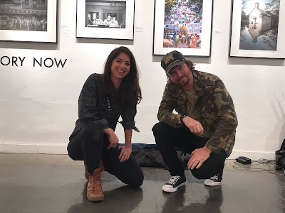 photo of photographers Gabriela E. Campos and Ryan Vizzions in front of their photographs in Monroe Gallery, Santa Fe