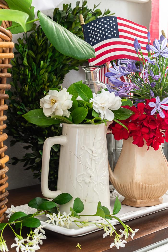 chippy ironstone pitcher with white camellia blooms, basket, greenery, usa flags