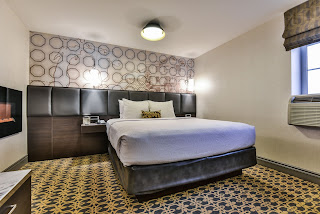One of the bedrooms at the Champlain Waterfront Hotel with a king size bed and wall fireplace.