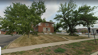 Small brick building, lawn, parking lot