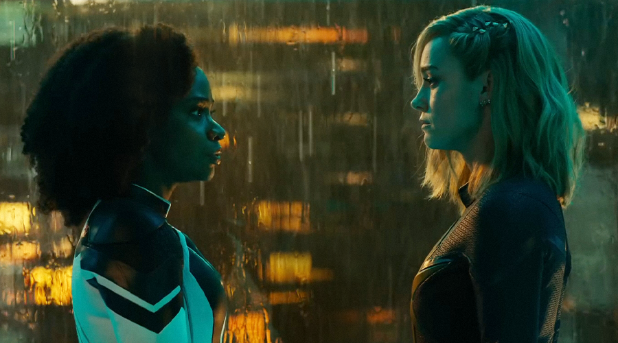 Brie Larson as Carol Danvers / Captain Marvel and Teyonah Parris as Monica Rambeau having a conversation by a window with water running down it.