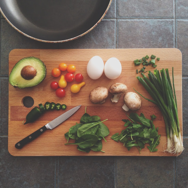 Assorted fresh vegetables and herbs on a wooden cutting board for healthy cooking and meal preparation