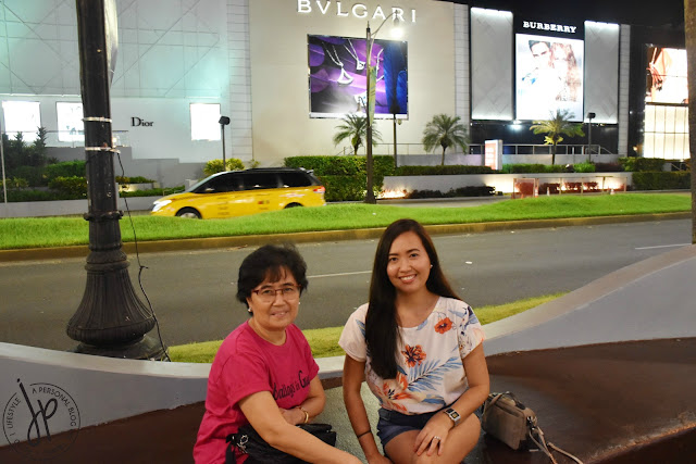 mother and daughter sitting at concrete bench along shopping street