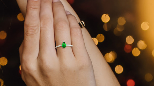 a woman wearing a solitaire emerald ring