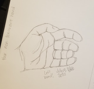 A photograph of a pencil drawing in a sketchbook. The drawing is of a relaxed left hand, palm to the viewer.