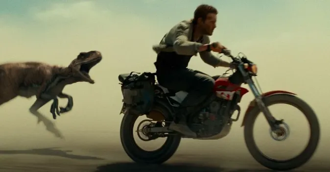 Chris Pratt being chased by a velociraptor on a Montessa trials bike in Jurassic World Dominion