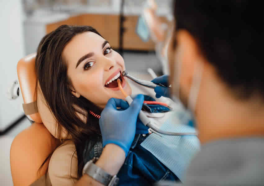 Imagem mostra uma mulher na cadeira do dentista.