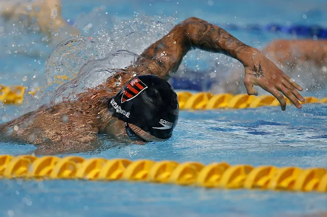 Com a touca do Flamengo, Guilherme Caribé está com o corpo na piscina, nadando no estilo Crawl