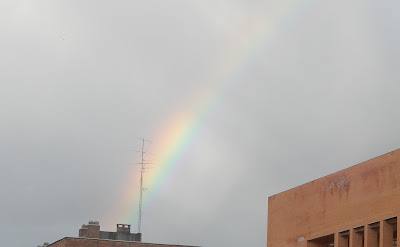 Arcoriris por encima de unos tejados. Se ve una antena de telefoníai