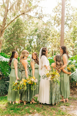 bride with bridesmaids in sage dressed holding green and yellow bouquets