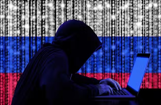 A Russian hacker working on a laptop and Russian flag in the beckground