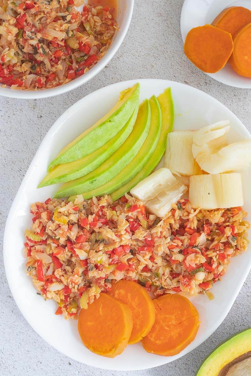 A serving of saltfish with sweet potatoes, boiled cassava, and avocado.