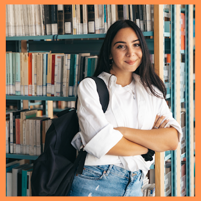 A female college student standing in front of a library bookcase full of books