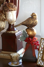 Bird finial with ribbon, holly leaves and Christmas berries and gold glitter acorns tied with ribbon dangling from the lamp.