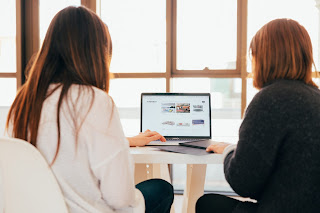 Kuvassa on kaksi naista tietokoneen edessä.