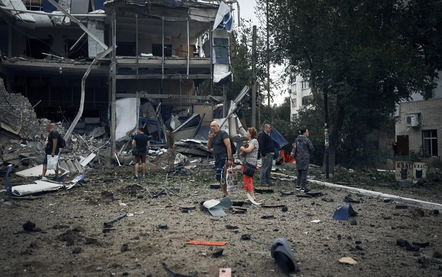 People stand in front of destroyed buildings after Russian shelling in Mykolaiv, Ukraine, on Wednesday, Aug. 3, 2022. (AP Photo/Kostiantyn Liberov)