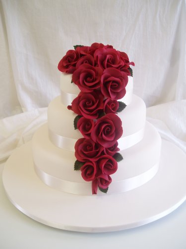 Gorgeous white wedding cake with elegant and romantic draping and blood red
