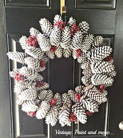 Vintage, Paint and more... This is a gorgeous pine cone wreath diy'd with found pine cones, spray painted white and sprinkled with snow glitter and red berries.  Perfect for your front door through the whole winter.