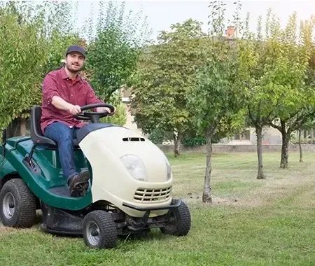 Jardinier tondant la pelouse sur une tondeuse autoportée